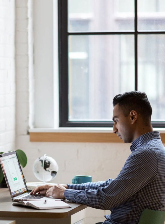 Man sitting at a desk working on a laptop.