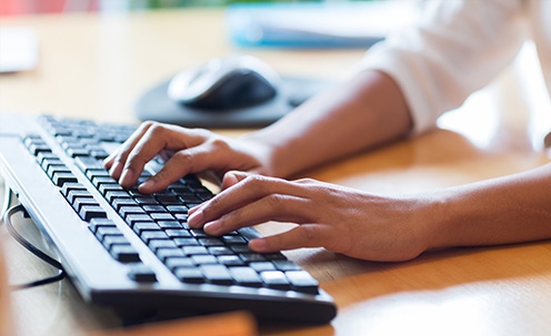 Closeup of a woman typing on a keyboard.