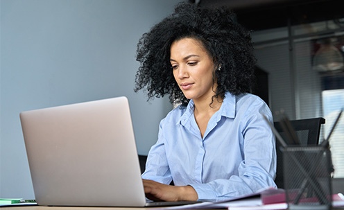A woman with large curly hair typing on a laptop.